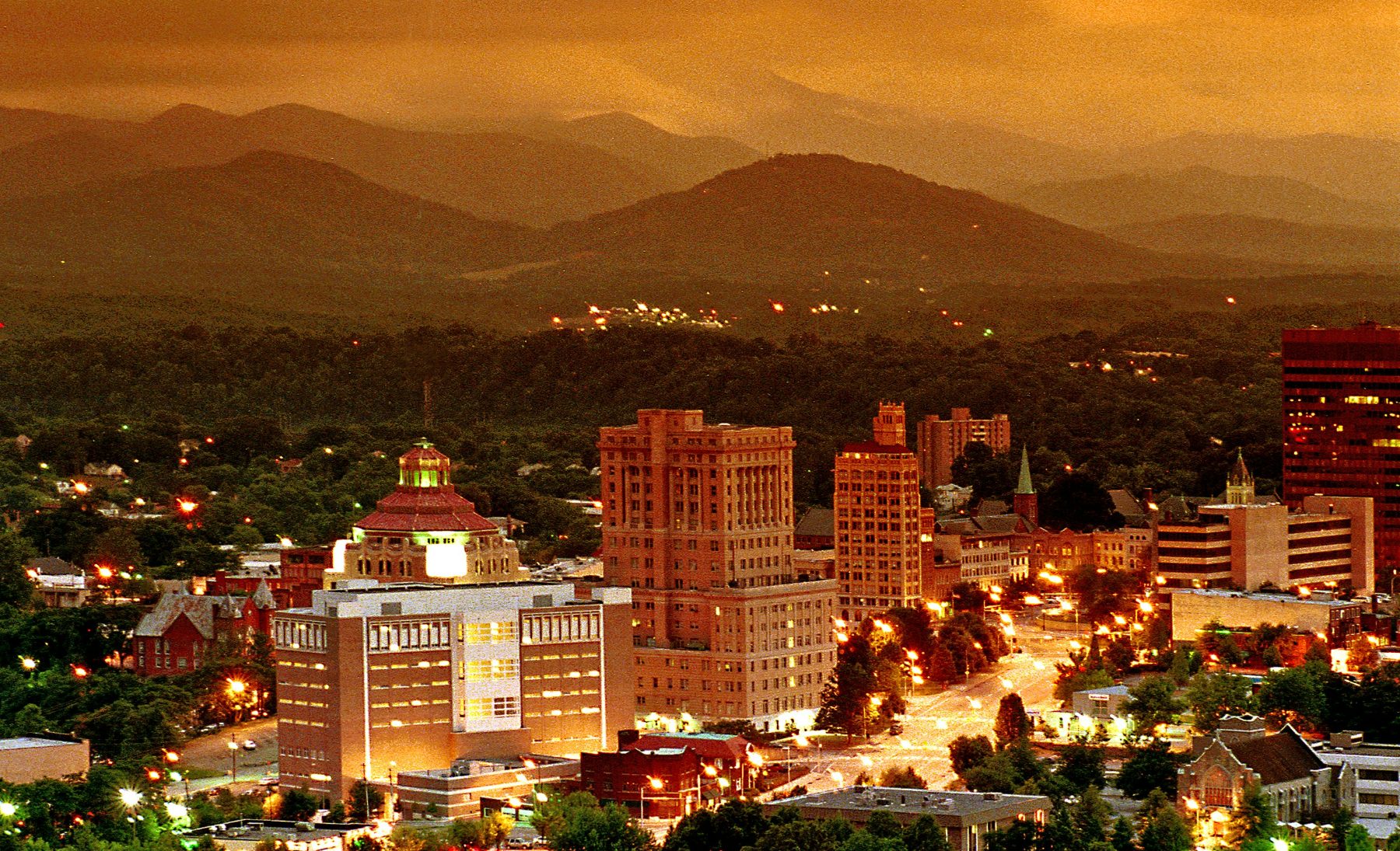 Downtown Asheville skyline below the Blue Ridge Mountains at dusk